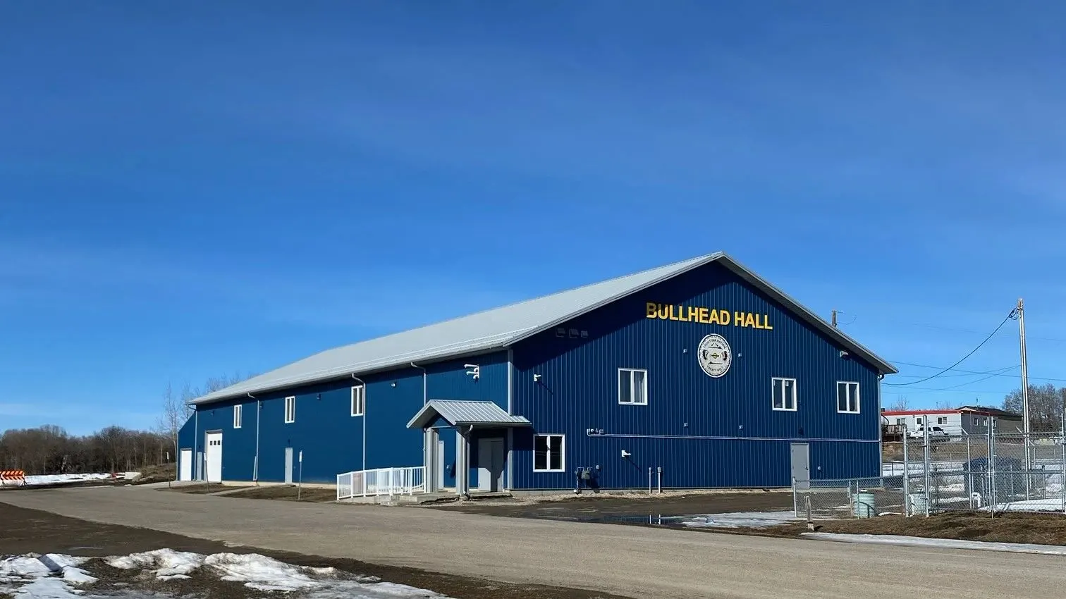 A completed blue steel-clad community hall under a clear sky